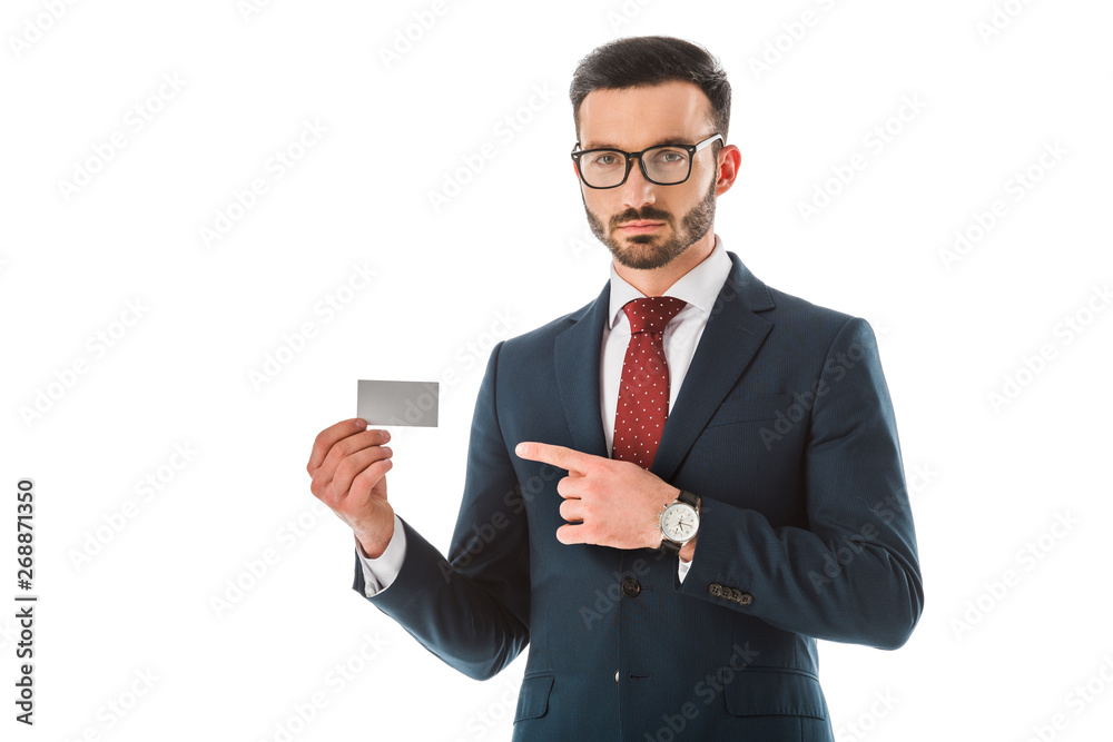 serious businessman pointing with finger at blank business card and looking at camera isolated on white serious businessman pointing with finger at blank business card and looking at camera isolated on white