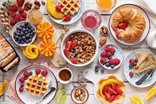 Happy breakfast with granola, croissant, fresh waffles, fruits and berries. 