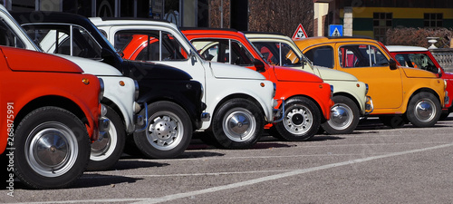  A row of colorful vintage Fiat 500 s  in a roadside parking lot on a sunny day. photo