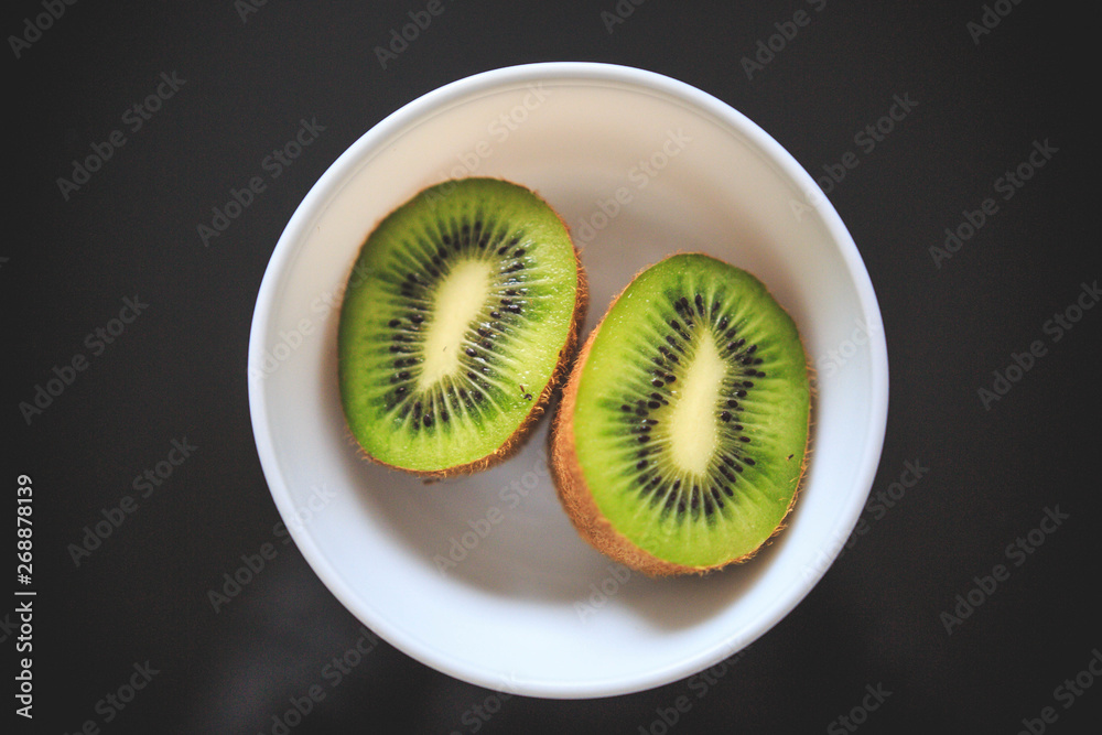 Close-up of kiwi halves in the bowl with exotic green color and black background. Close-up of kiwi halves in the bowl with exotic green color and black background.