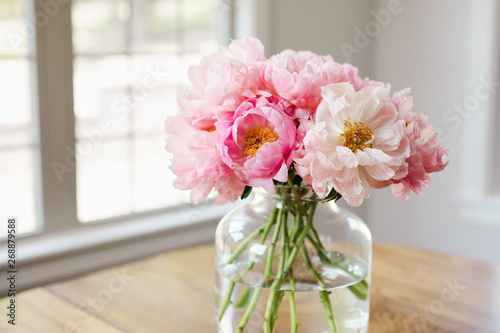 bouquet of pink peonies in a glass vase in a light filled room