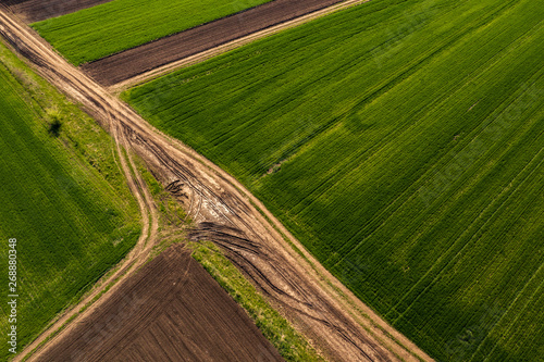 Aerial view of dirt road through countryside and agricultural field