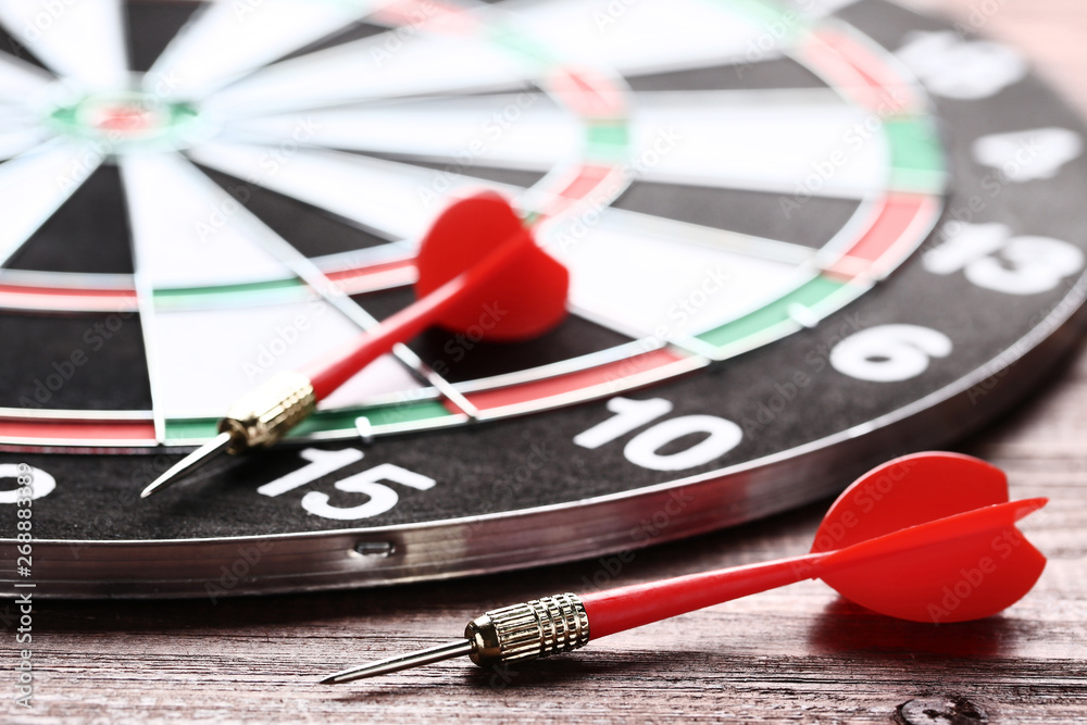 Dartboard with darts on brown wooden table Dartboard with darts on brown wooden table