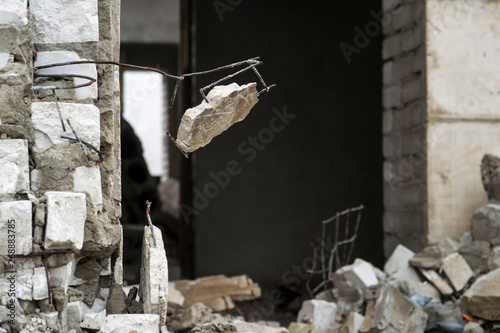 Entrance to the destroyed brick building with a hanging piece of concrete in the foreground. Background. Copy space