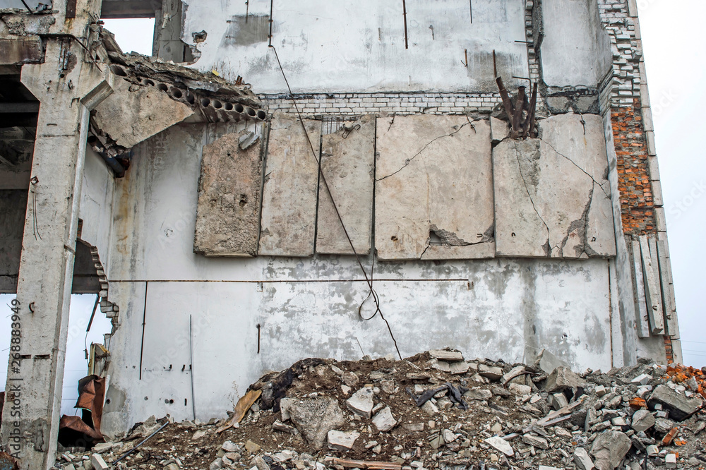 The concrete wall of the destroyed large building with hanging concrete slabs on the reinforcement. Background The concrete wall of the destroyed large building with hanging concrete slabs on the reinforcement. Background