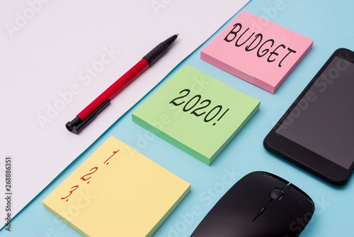 Word writing text Budget 2020. Business photo showcasing estimate of income and expenditure for next or current year Note papers and stationary plus gadgets placed sideways above backdrop
