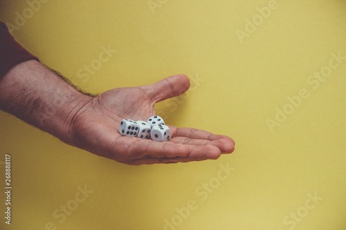 Playing dice in hand, isolated on yellow background.
