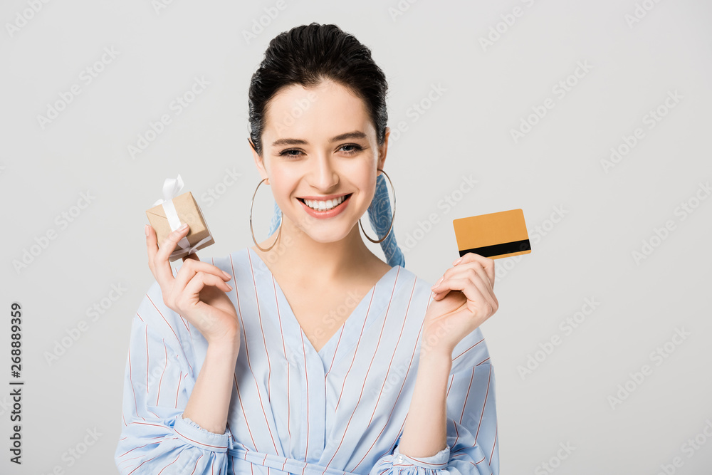beautiful stylish girl holding gift box with Credit card and smiling isolated on grey beautiful stylish girl holding gift box with Credit card and smiling isolated on grey
