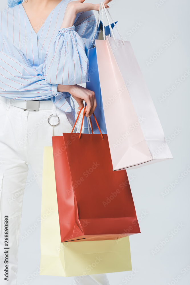 partial view of stylish girl with shopping bags isolated on grey