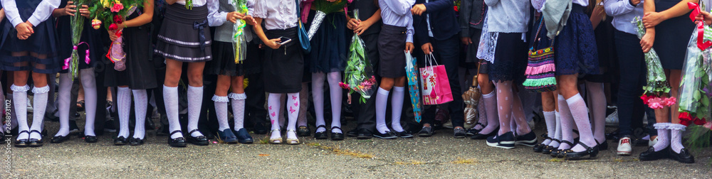 Obraz premium children enrolled in the first class with bouquets of flowers in the hands on the school solemn parade