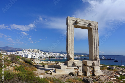 Iconic and unique Temple of Apollon or Portara (Gate) with breathtaking views to port - town and castle of Naxos island and the Aegean blue sea, Cyclades, Greece