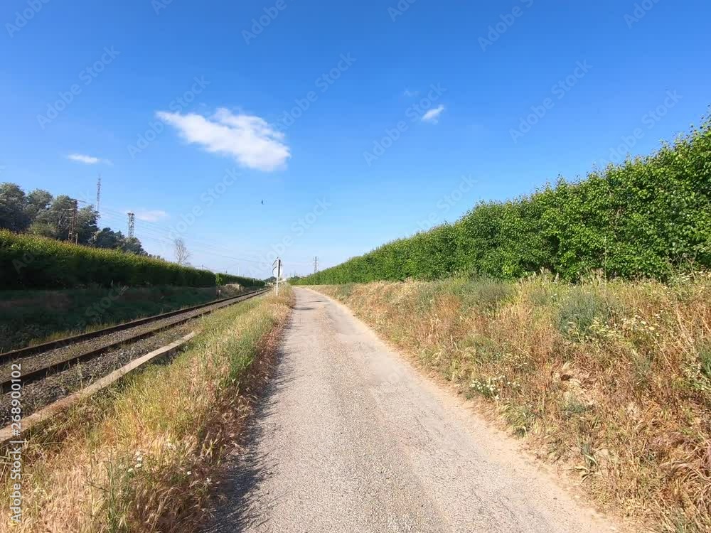 Stone road next to train tracks and fruit trees in sunny day. Stone road next to train tracks and fruit trees in sunny day.