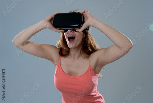 Portrait of cheerful and shocked young woman wearing Virtual Reality headset exploring 3D world