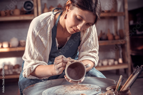 Fototapeta Stylish artisan making pottery, sculptor from wet clay on wheel
