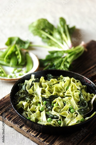 green fettuccine pasta with spinach leaves and green peas. ready meals, vegetarian cuisine. Italian food.