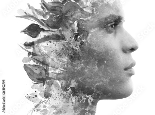 Paintography. Double exposure. Close up profile of man with strong features and flawless skin dissolving behind hand painted floral watercolor and ink painting, black and white