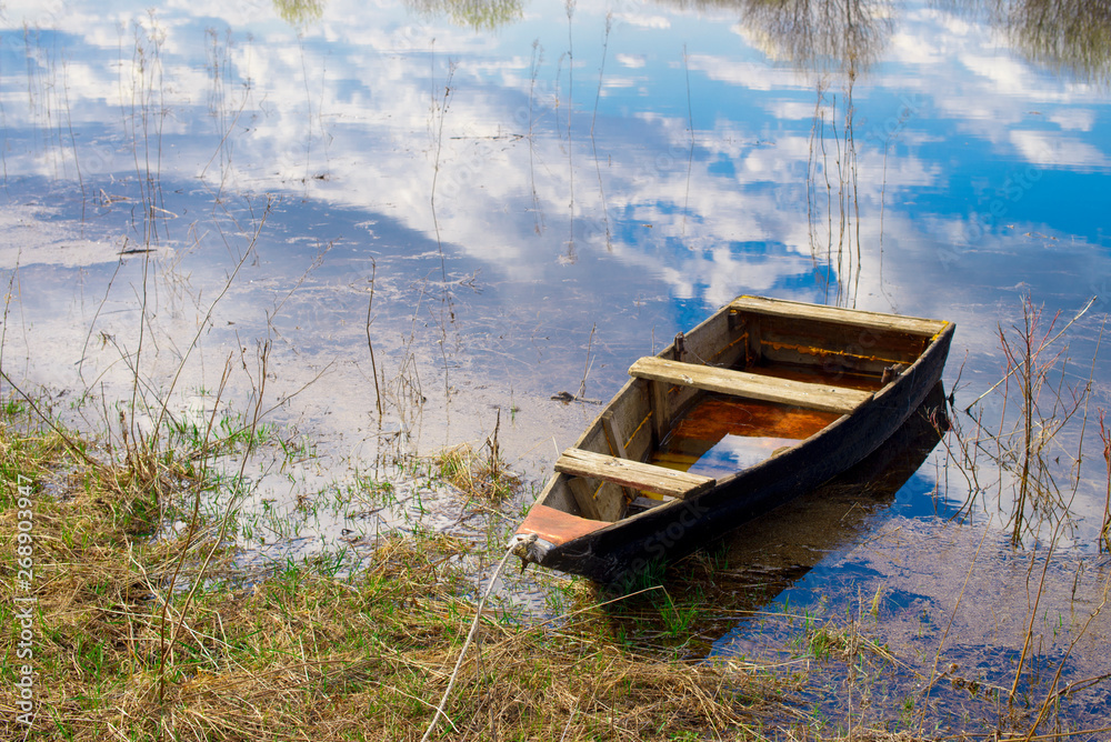Obraz premium Old wooden boat near the river. Spring flood