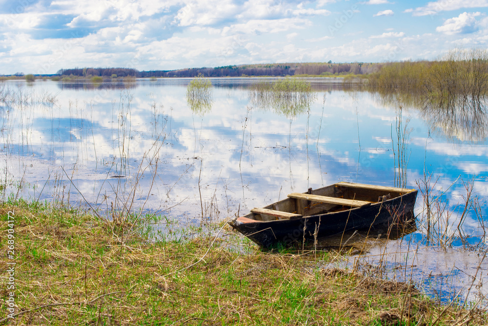 Fototapeta premium Old wooden boat near the river. Spring flood