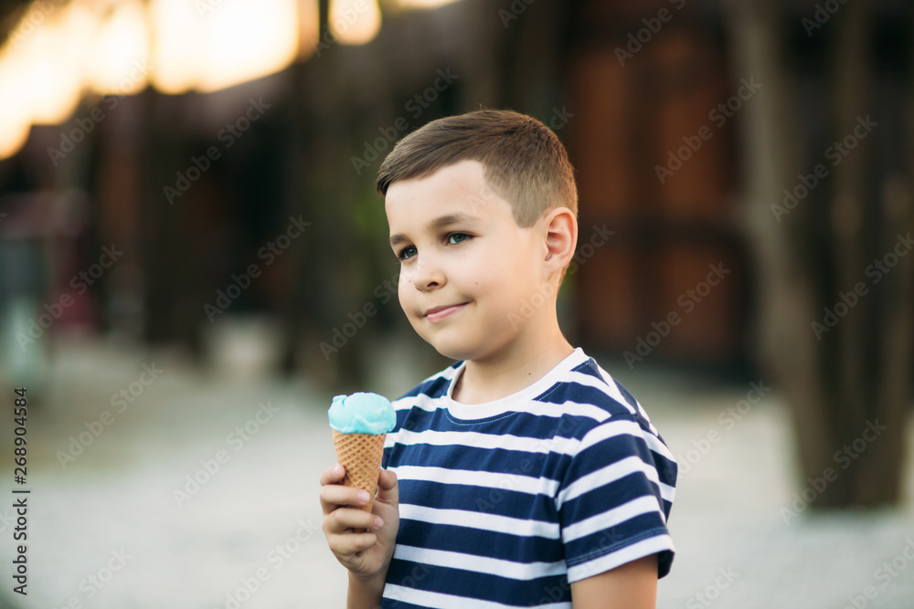 A little boy in a striped T-shirt is eating blue ice cream.Spring, sunny weather A little boy in a striped T-shirt is eating blue ice cream.Spring, sunny weather