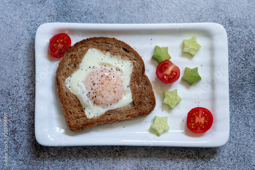 Tablou pe pânză Egg fried in a hole star-shaped toast with avocado and tomato