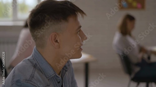 A student of 20 years old is attentively listening to the teacher. 4K