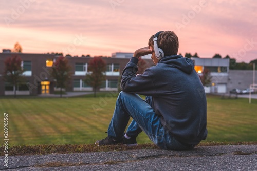 Upset teenager sitting on the ground all alone while listening to some music. photo