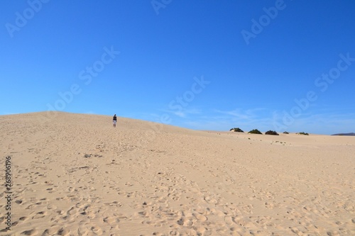 Unidentified woman standing at the sand dunes. Parque Natural de Corralejo at Fuerteventura, Canary Islands, Spain
