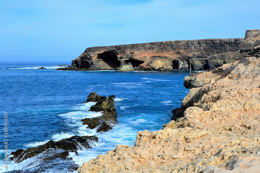 Limestones and rocks on the shore of Fuerteventura island at Ajuy village. Scenic view of shore with blue Atlantic ocean and waves hitting the cliffs.