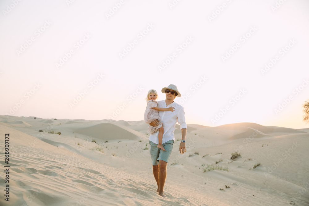 Father holding his little daughter in dress in the desert