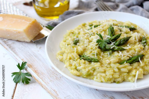 Italian risotto with spring asparagus and parmesan cheese on light background. Top view with copy space.