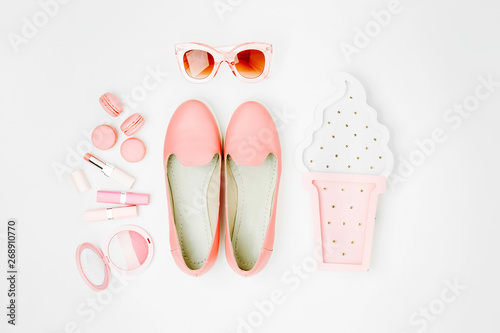 Flat lay of female fashion accessories, shoes, makeup products on pastel color background. Beauty and fashion concept