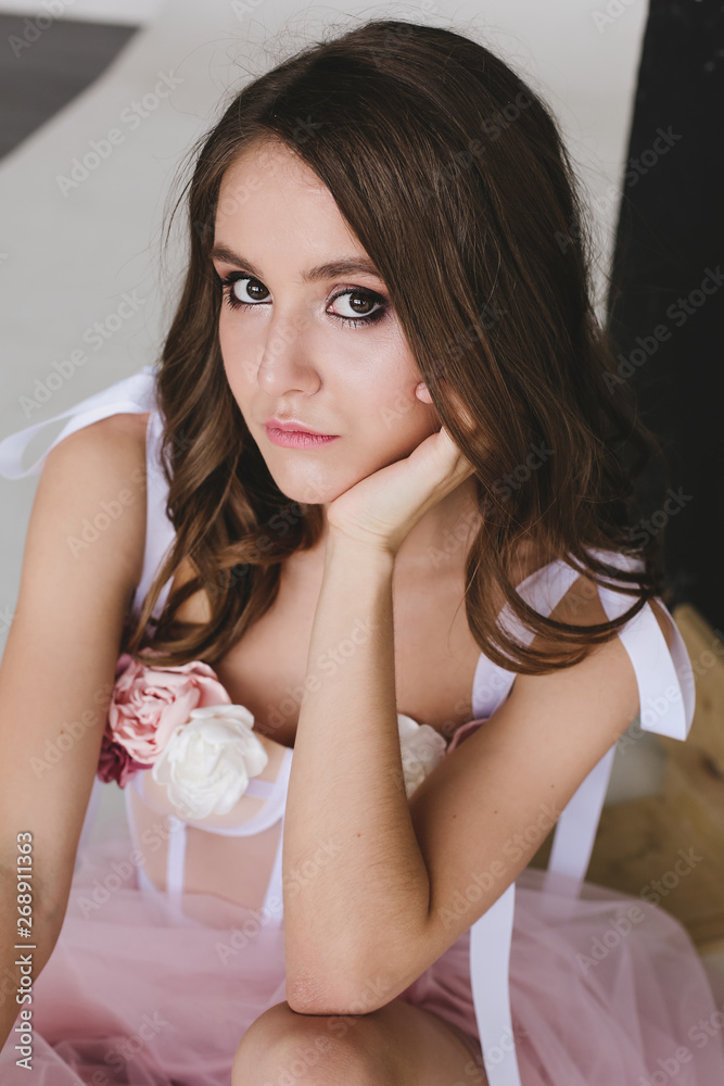 Naklejka premium attractive fashionable woman posing in pink dress on a white background in the studio