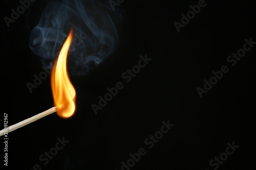 Burning matchstick on black background, closeup. Space for text