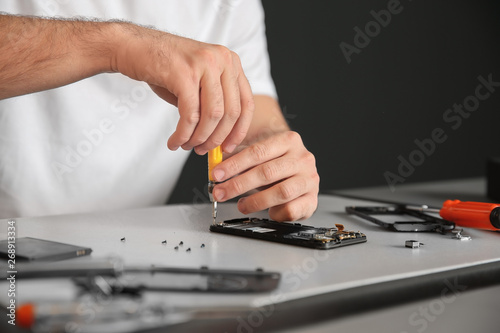 Technician repairing mobile phone at table, closeup