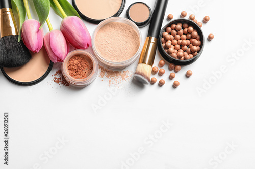Many different makeup products and spring flowers on white background, top view