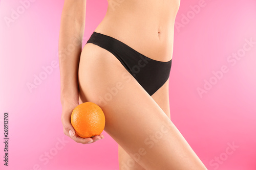Closeup view of slim woman in underwear with orange on color background. Cellulite problem concept