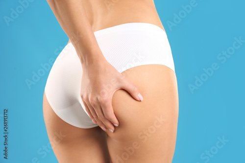 Closeup view of slim woman in underwear on color background. Cellulite problem concept