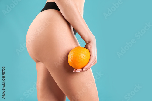 Closeup view of slim woman in underwear with orange on color background. Cellulite problem concept