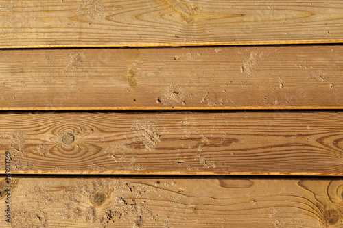 Wooden background. Boards in sand. Weathered wooden boardwalk on the sand. Natural materials. Wood surface texture