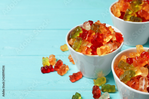 Bowls with delicious jelly bears on wooden table. Space for text