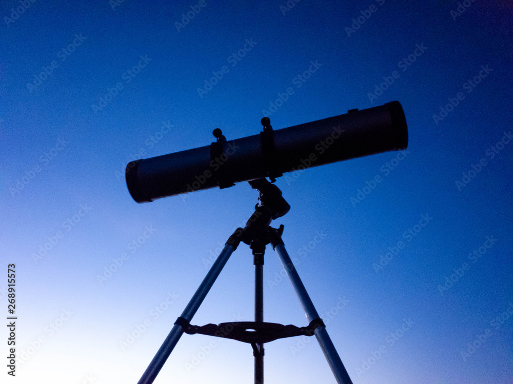 Telescope on a tripod at night in nature against the backdrop of the starry sky.
