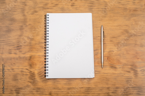 White note pad with steel pen on a wooden table. Copy space.