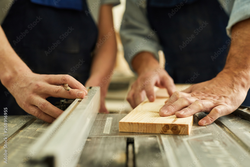 Closeup of senior carpenter working with apprentice in joinery workshop, copy space