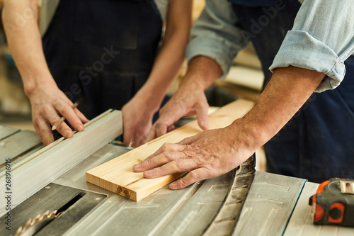 Close up of senior carpenter working with apprentice in joinery workshop, copy space