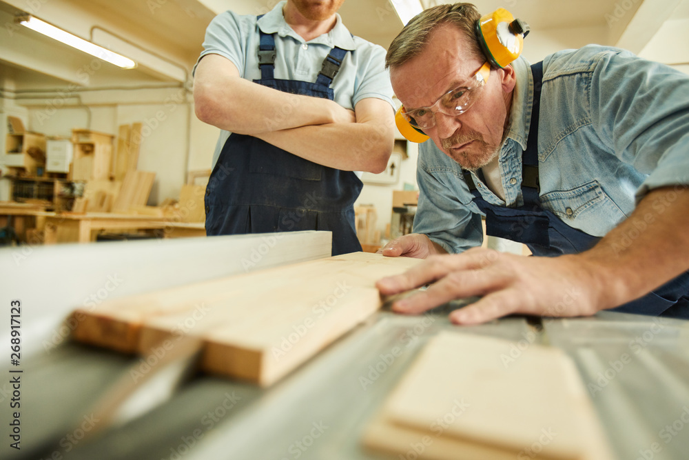 Portrait of carpenter cutting wood using disksaw while working in joinery workshop, copy space Portrait of carpenter cutting wood using disksaw while working in joinery workshop, copy space