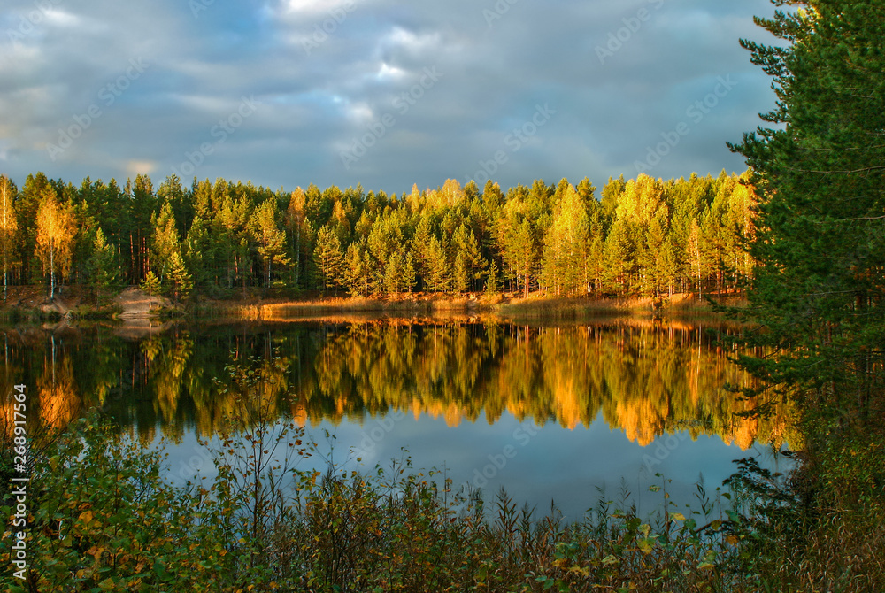 The forest lake at sunset, with reflection of sky and forest on a water smooth surface, Russia, Mari El The forest lake at sunset, with reflection of sky and forest on a water smooth surface, Russia, Mari El