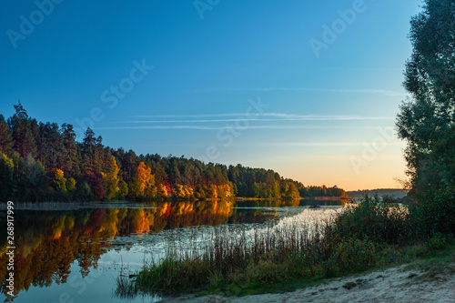 Silence at the forest lake at sunset, with reflection of sky and forest on a water smooth surface, Russia, Mari El