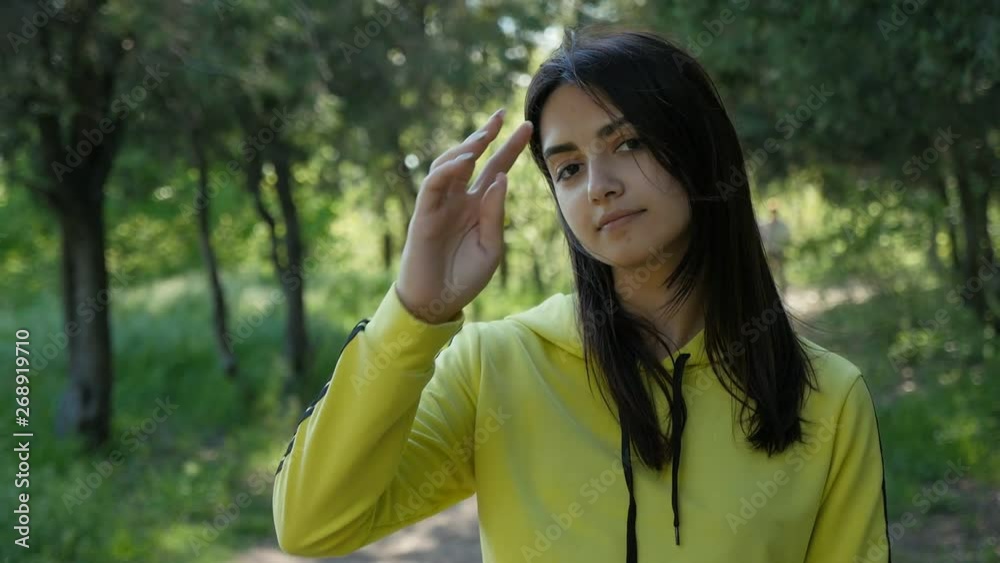 joyful beautiful girl in a yellow sports suit smiling in the park among green grass and trees in sunny day in slow motion joyful beautiful girl in a yellow sports suit smiling in the park among green grass and trees in sunny day in slow motion