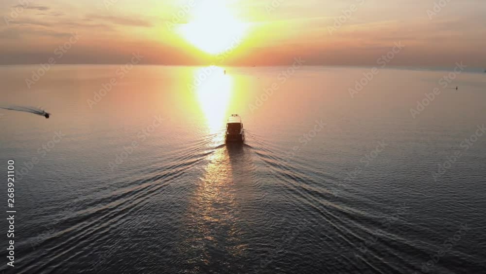 Follow white ship yacht - Aerial sunset top Lighthouse view with ships in the background - Warm setting sun landscape scenery during Golden Hour