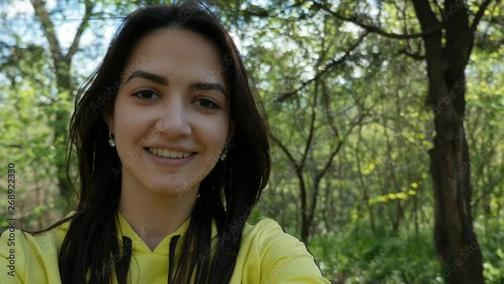 young beautiful positive girl in a yellow sports suit doing video selfie and turning with camera in the park among green grass and trees in sunny day in slow motion young beautiful positive girl in a yellow sports suit doing video selfie and turning with camera in the park among green grass and trees in sunny day in slow motion